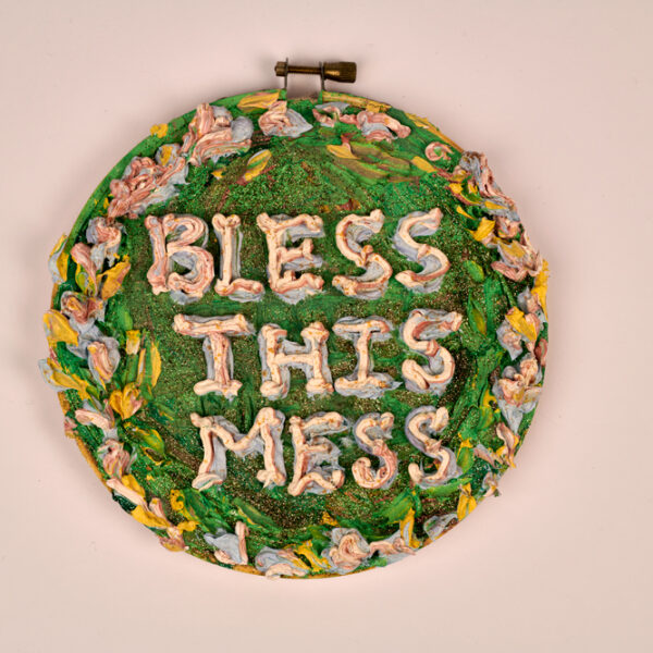 Holly Clark, “Bless This Mess”, oil paint, embroidery hoop, glitter and canvas,  8” oval, 2020.