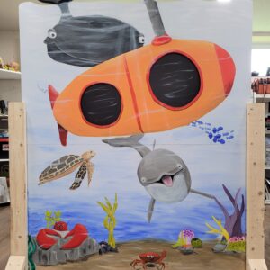 Picture of a stand up photo stand in board where the person standing behind it's head appears to be in a submarine in the ocean.