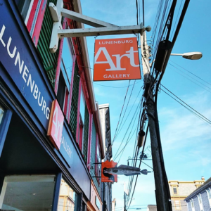 The exterior of the Lunenburg Art Gallery, angled skyward to feature the gallery sign hanging over the sidewalk
